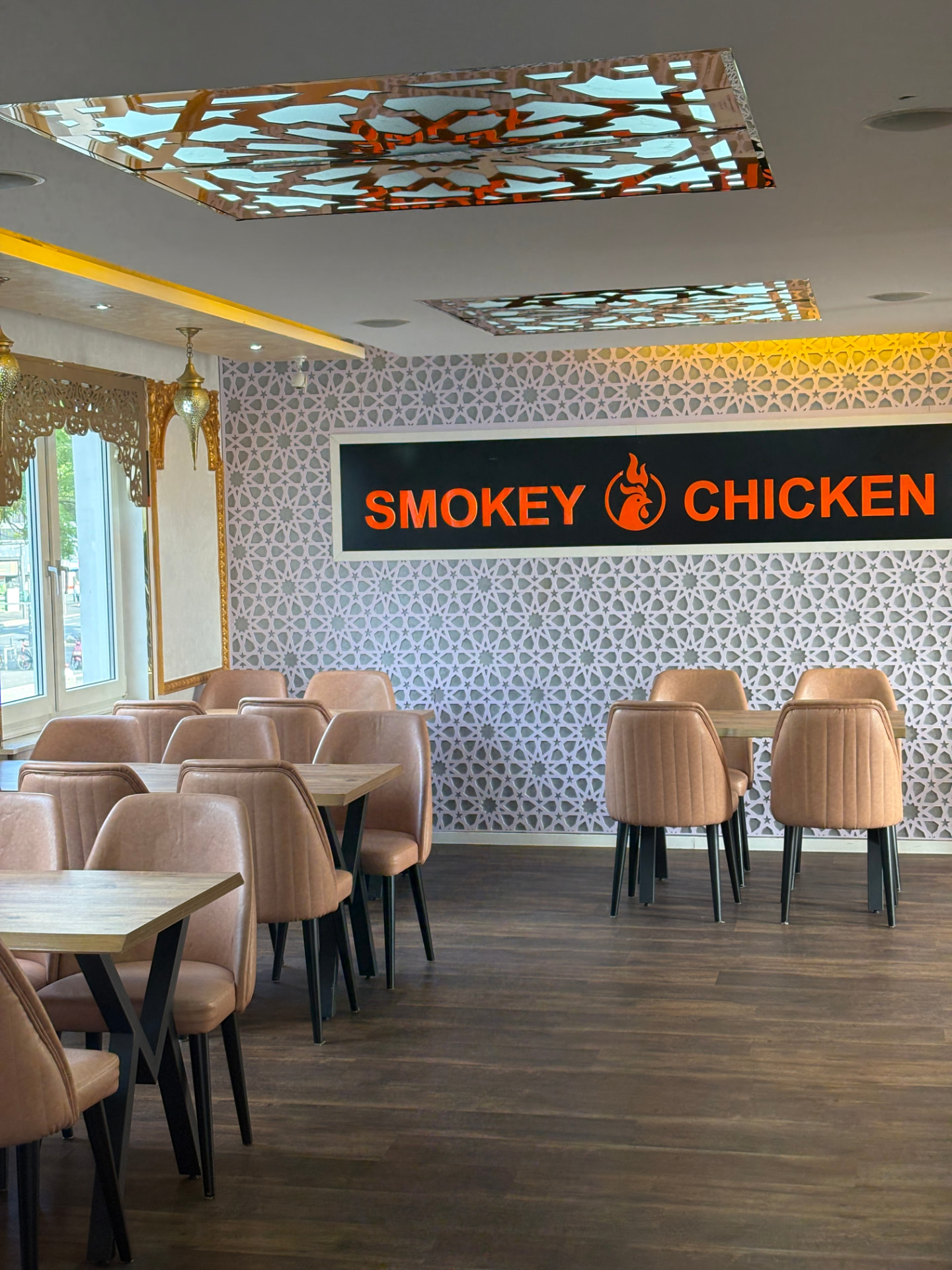 Innenraum von Smokey Chicken in Bad Godesberg mit beleuchtetem Schriftzug und geometrischer Musterwand