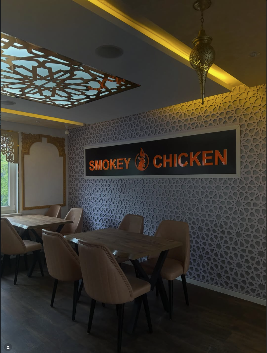 Innenraum von Smokey Chicken in Bad Godesberg mit beleuchtetem Schriftzug und geometrischer Musterwand